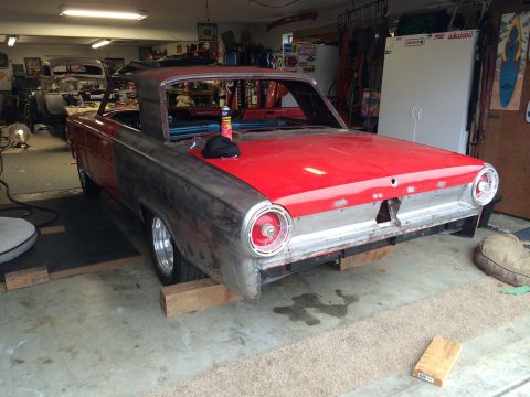 1964 Ford Fairlane - A classic car in a garage is being worked on, with its rear end visible and partially unpainted body panels.