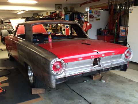 1964 Ford Fairlane - A classic car is parked in a garage, showing its red roof and bare metal body panels during a restoration project.