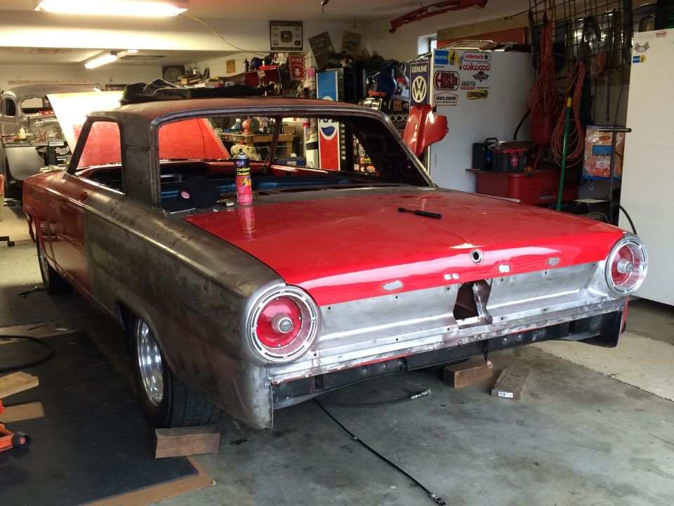 1964 Ford Fairlane in garage, undergoing restoration. Red top, bare metal sides