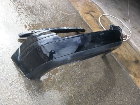 2002 Volkswagen Jetta - A detached black car bumper rests on a wet, textured surface, with a white cord coiled nearby.