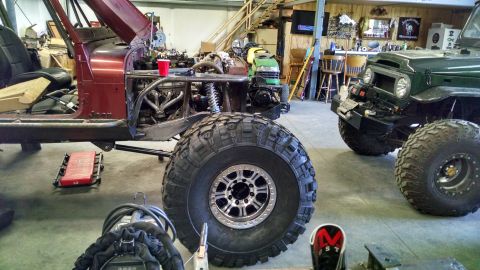 Maroon Jeep CJ-series with large off-road tires, undergoing customization
