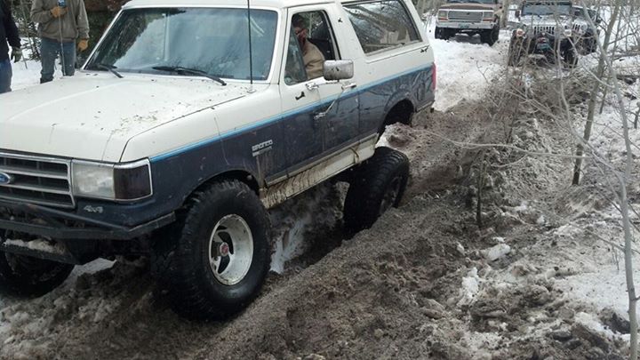 1989 Ford Bronco stuck in snow, with other vehicles behind it