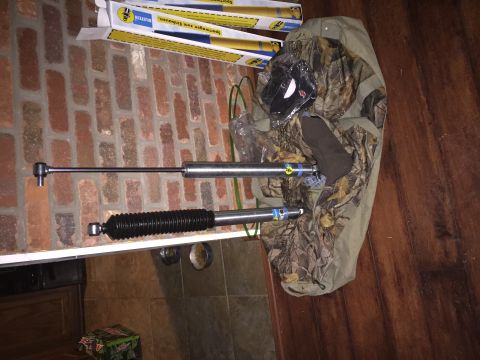1994 Ford Bronco - Two Bilstein shock absorbers and their packaging are displayed on a shelf, with a camouflage jacket draped nearby.