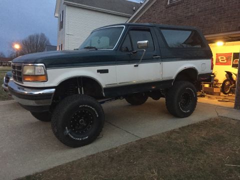 1994 Ford Bronco - This lifted 1994 Ford Bronco has a two-tone paint scheme and is parked in a driveway.
