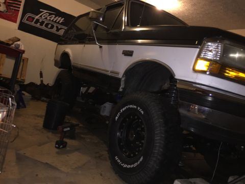1994 Ford Bronco - A two-tone Ford Bronco is shown with its front end angled towards the camera, appearing to be undergoing modifications.