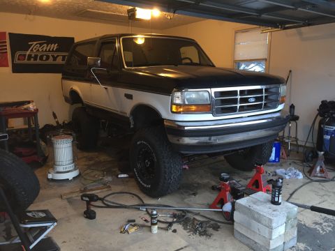 1994 Ford Bronco - This lifted 1994 Ford Bronco is undergoing maintenance in a garage, with its front end supported by jack stands.