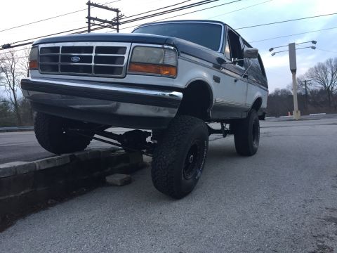 1994 Ford Bronco - 1994 Ford Bronco with lifted suspension is parked with one tire on a low wall.