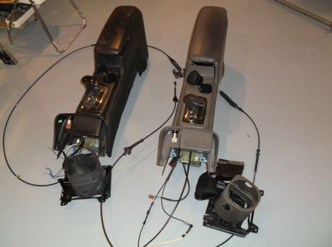 1999 Mercury Grand Marquis - Two disassembled center consoles, likely from a car, are shown with their gear shifters and exposed wiring.
