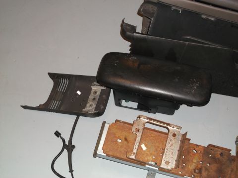 1999 Mercury Grand Marquis - Several disassembled car interior components, including a center console armrest and trim, are laid out on a gray surface.