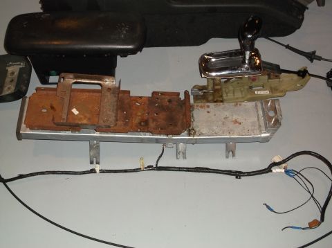 1999 Mercury Grand Marquis - Disassembled vehicle interior components, including a shifter and console base, are laid out on a gray surface.