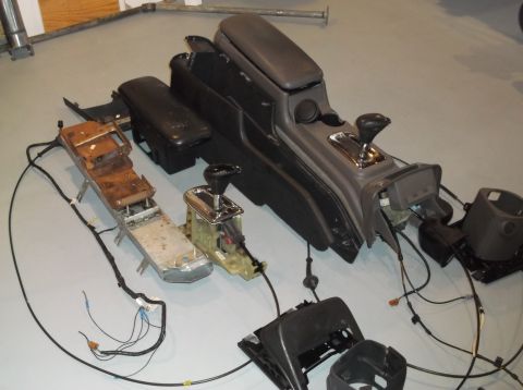 1999 Mercury Grand Marquis - Various parts of a car's center console, including the shifter mechanism and surrounding trim, are laid out on the floor.