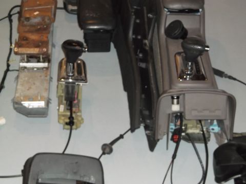 1999 Mercury Grand Marquis - Disassembled car interior components, multiple gear shifters and console sections, are visible.