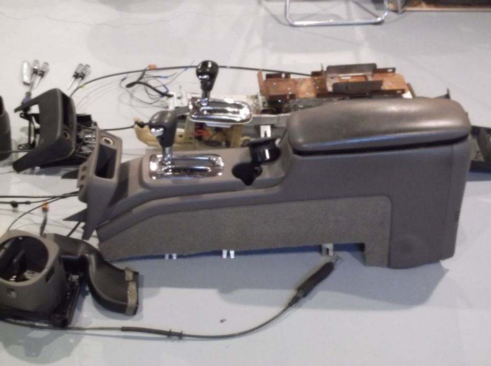 Car's center console and shifter assembly are disassembled on the floor