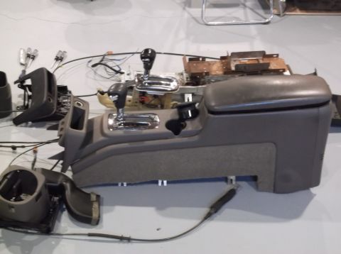 1999 Mercury Grand Marquis - Disassembled car interior console with gear shifter and surrounding parts laid out.