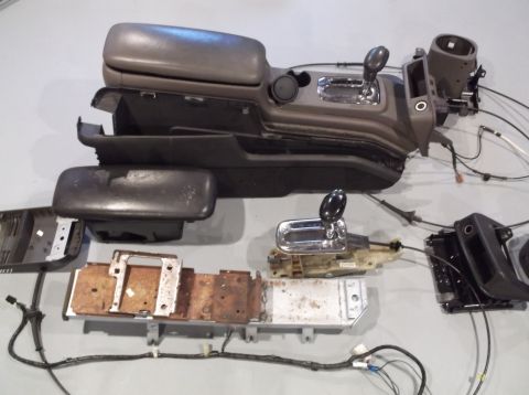 1999 Mercury Grand Marquis - Disassembled car interior components, including the center console and gear shifter, are laid out on a flat surface.