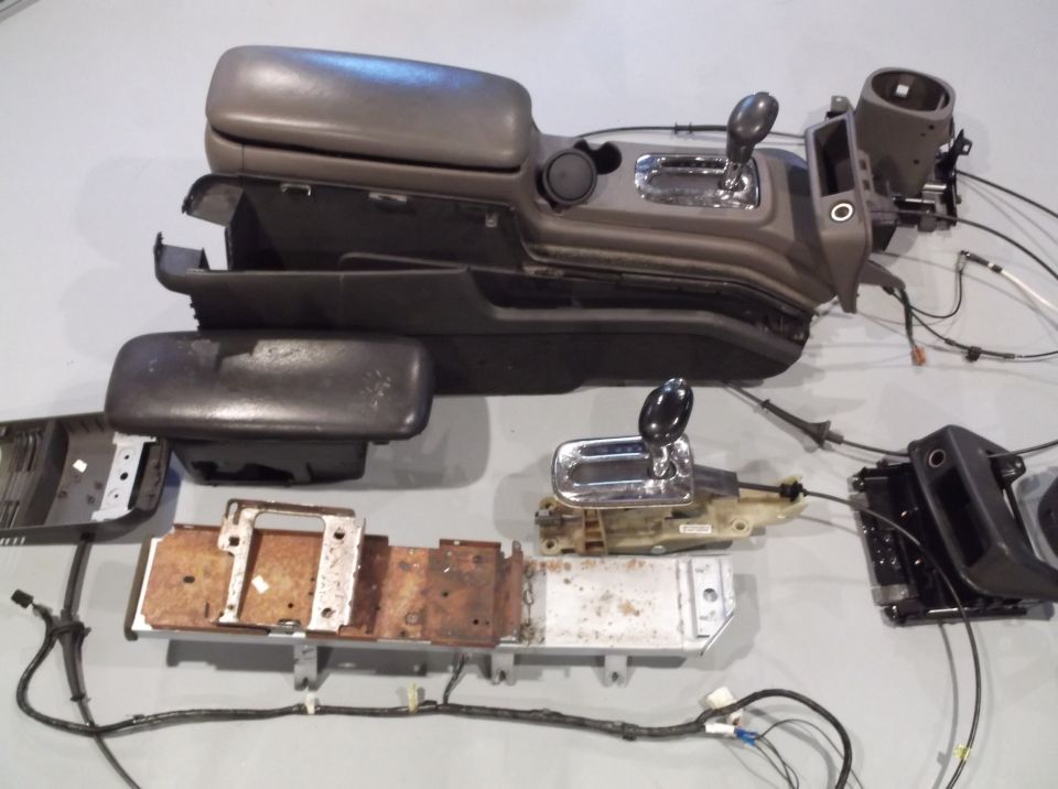 Car's center console and shifter assembly disassembled, showing various parts and wiring