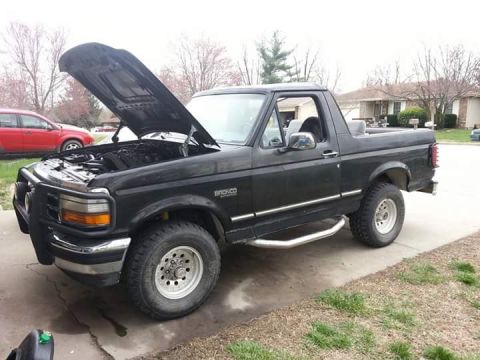 1994 Ford Bronco - This 1994 Ford Bronco is parked on a driveway with its hood open, revealing the engine bay.