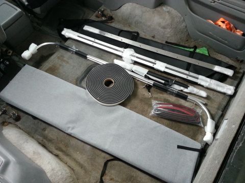 1994 Ford Bronco - Various automotive parts and supplies are organized on the floor inside a vehicle's interior.