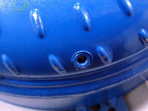 2001 Mercury Grand Marquis - Close-up of a blue metal component, possibly a transmission part, showing a hex bolt hole and textured surface.