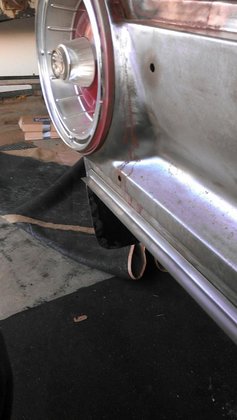 1964 Ford Fairlane - Close-up of the rear quarter panel and wheel well of a 1964 Ford Fairlane, showing chrome trim and a red-accented wheel.