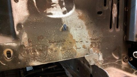 1964 Ford Fairlane - Close-up of a rusted metal component with various markings and stamped numbers visible.