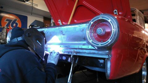 1964 Ford Fairlane - A person is welding the rear body panel of a vintage automobile in a garage.