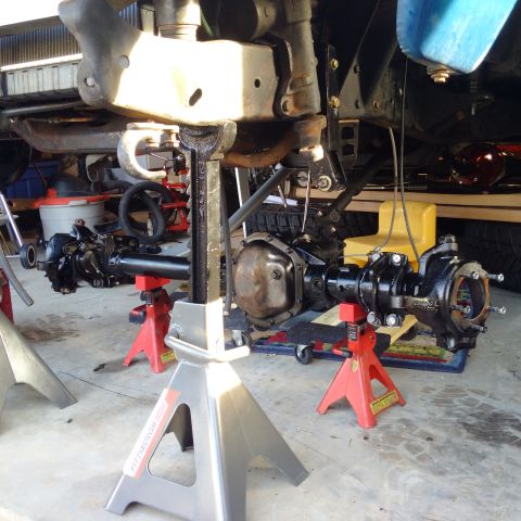 1978 Ford Bronco - The undercarriage of a vehicle is raised on jack stands for maintenance, showing the axles and suspension.