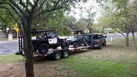1986 Ford Bronco - A trailer carries a Jeep Wrangler, a utility vehicle, and a pickup truck.
