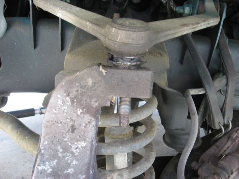 1994 Ford Bronco - This image shows a close-up of a vehicle's suspension system, focusing on a rusty mechanical part and coil spring.