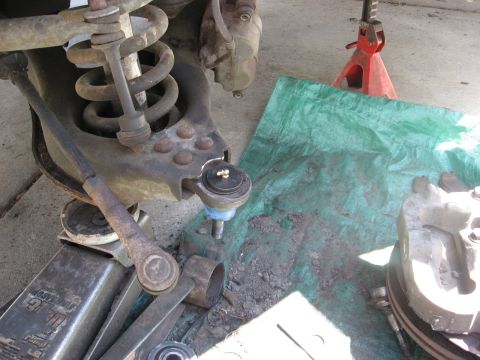 1994 Ford Bronco - Close-up of a vehicle's front suspension ball joint, resting on a green tarp.