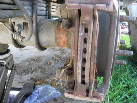 1994 Ford Bronco - Close-up of a rusty rear axle brake assembly, showing wear on the rotor and caliper.