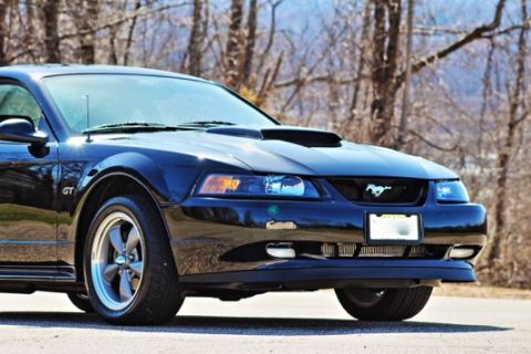 2002 Ford Mustang - A black 2002 Ford Mustang GT is shown from the front quarter angle, highlighting its iconic design.