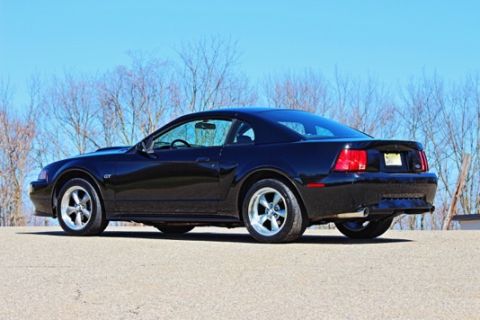 2002 Ford Mustang - The rear quarter view of a black Ford Mustang GT shows its distinctive taillights and dual exhaust pipes.
