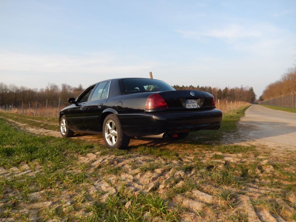 Black 2003 Mercury Marauder parked on a dirt road with grass and trees in the background