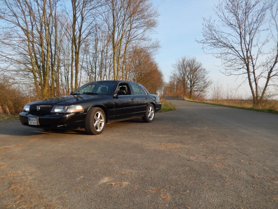 Black 2003 Mercury Marauder parked on a paved road with trees in the background