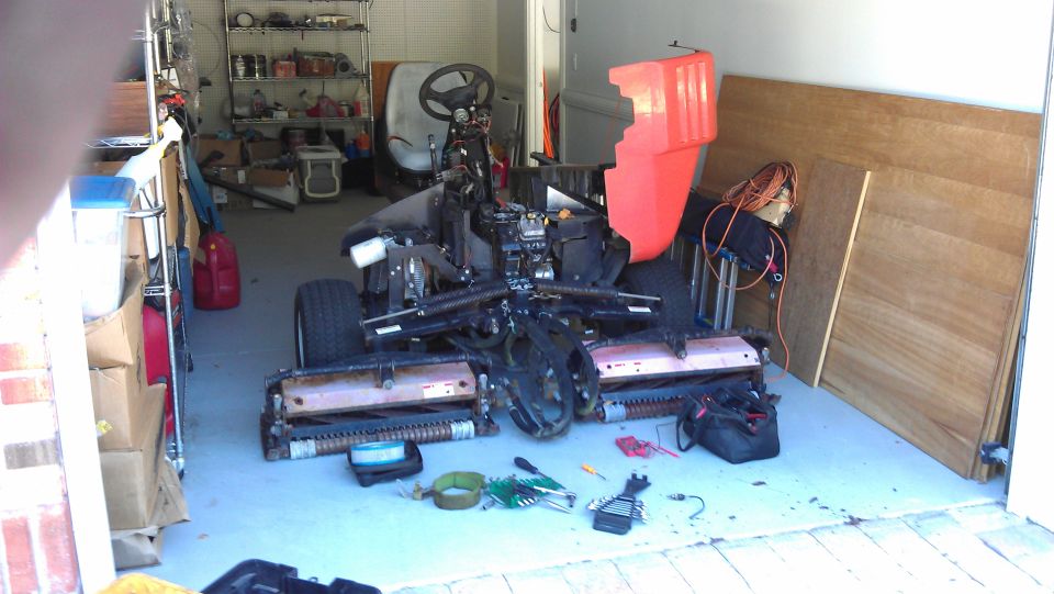 Disassembled lawn mower with tools on the floor