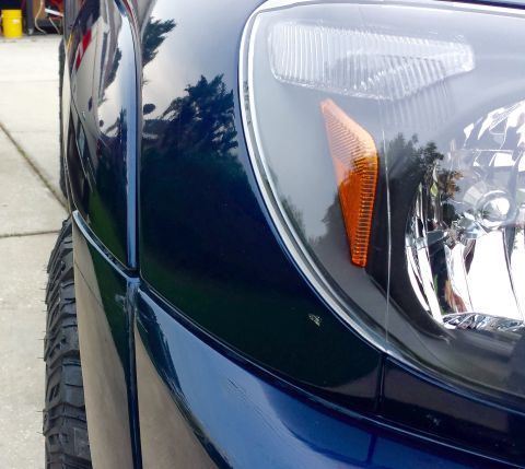 2005 Toyota 4Runner - Detail of a dark blue SUV's front fender and headlight assembly, with a visible tire and a watermark.