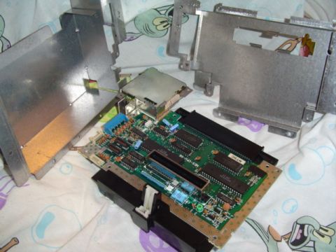 1999 Ford Taurus - An electronic device, possibly a game console, disassembled to reveal its internal circuit board and metal casing components.