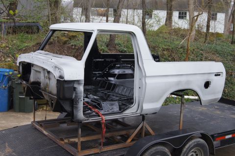 1979 Ford Bronco - This stripped-down truck body is undergoing restoration work, sitting on a trailer outdoors.