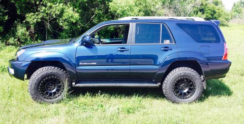 2005 Toyota 4Runner - This blue SUV has a lifted suspension and off-road tires, suggesting a model year around 2003 based on its body style.