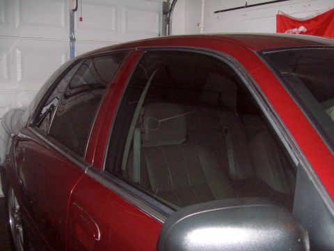 2004 Ford Crown Victoria - Side profile of a red 2004 Ford Crown Victoria with tinted windows.