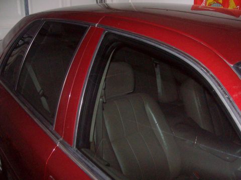 2004 Ford Crown Victoria - The interior of a red sedan is visible, with a focus on the rear seating area and tinted windows.