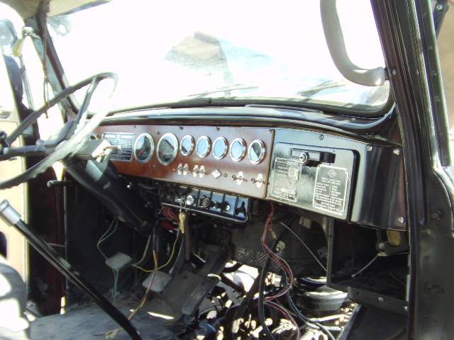 Truck dashboard with wood grain trim, multiple gauges, and exposed wiring