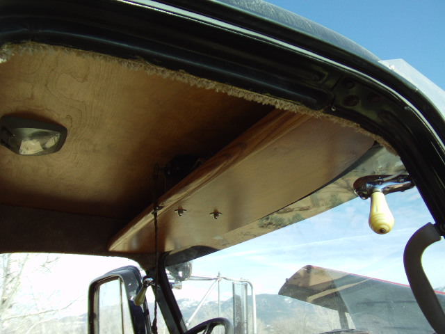 Interior view of a truck cab with wood paneling and a yellow knob