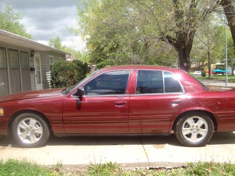 2004 Ford Crown Victoria - This red 2004 Ford Crown Victoria is shown from the side, with tinted windows.