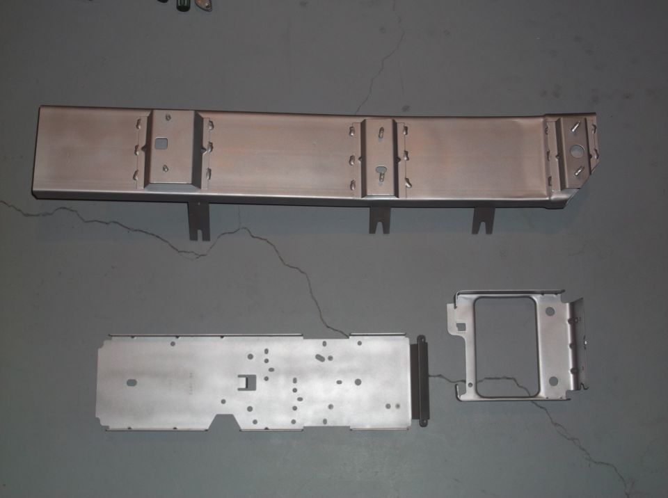 Metal automotive console parts on a gray floor