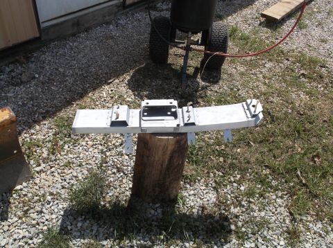 1999 Mercury Grand Marquis - A car bumper part is mounted on a log outdoors, with a sandblaster visible behind it.