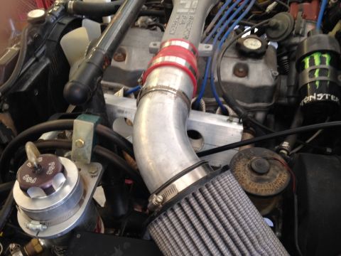 1987 Suzuki Samurai - Close-up view of an engine bay an aftermarket intake system and a Monster Energy drink can attached to the engine.