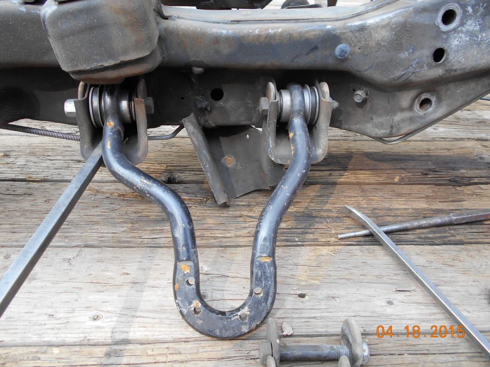 close-up of vehicle's front sway bar and mounting hardware on wooden surface