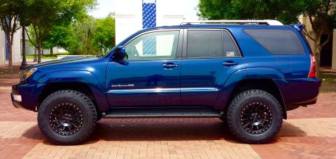 2005 Toyota 4Runner - Side view of a blue 2005 Toyota 4Runner SUV modified with off-road tires and black wheels.